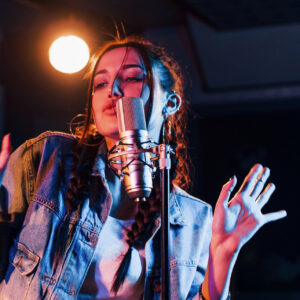 Young beautiful female performer sings and rehearsing in a recording studio