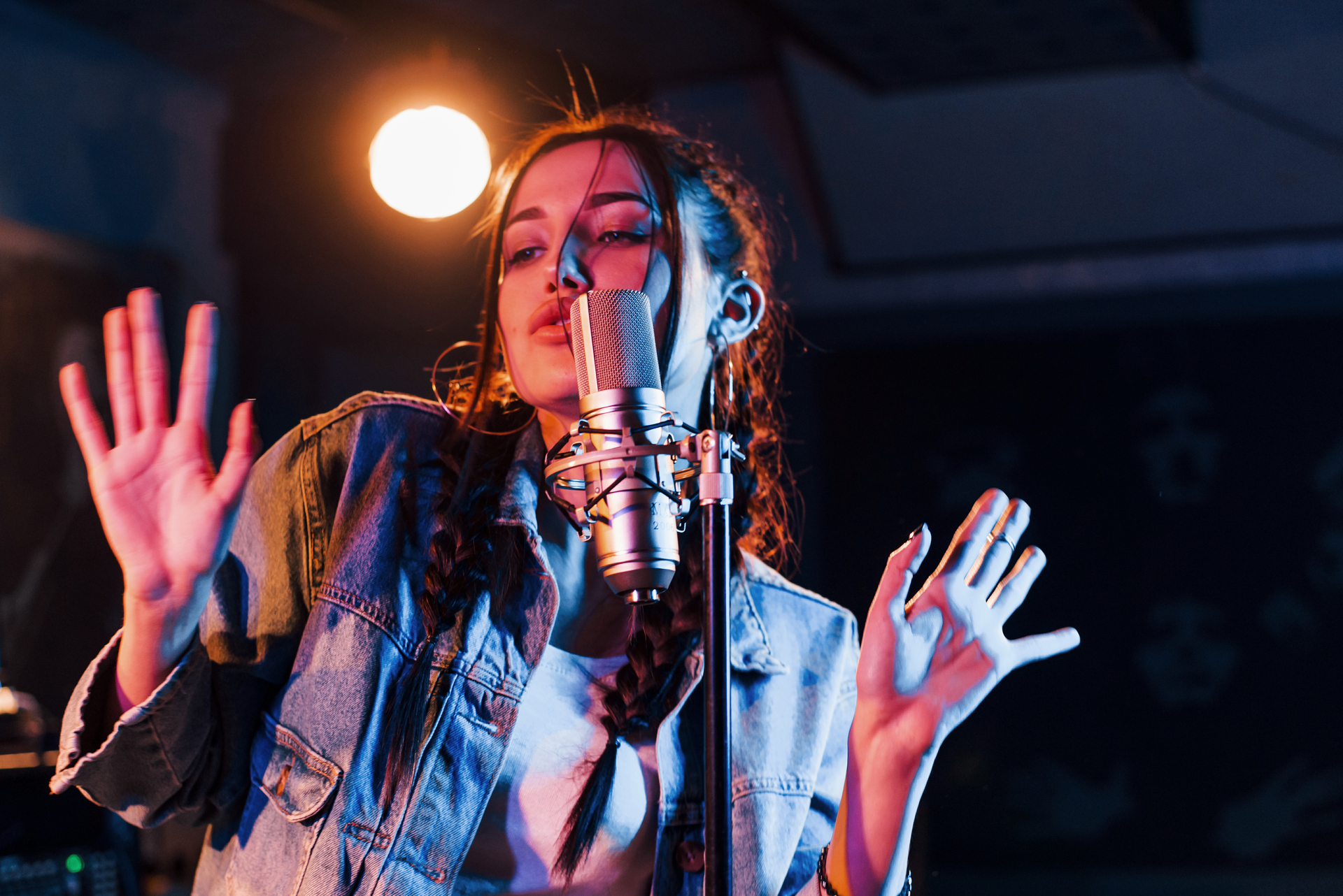 Young beautiful female performer sings and rehearsing in a recording studio